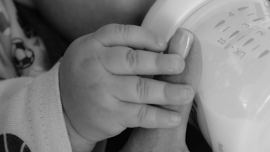 baby and adult hand on baby bottle